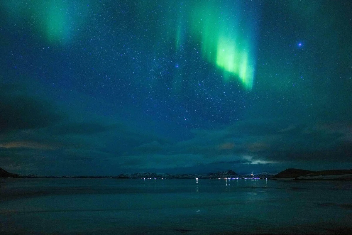 Northern lights in the night sky over Mývatn (Iceland). Polar aurorae are caused by the collision of charged particles in the solar wind with gases in the upper atmosphere. These collisions generate tiny flashes of light that fill the sky with veils of colour.